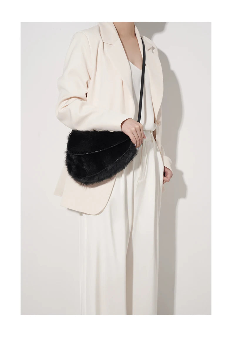 Person wearing a white outfit with a black fur bag 